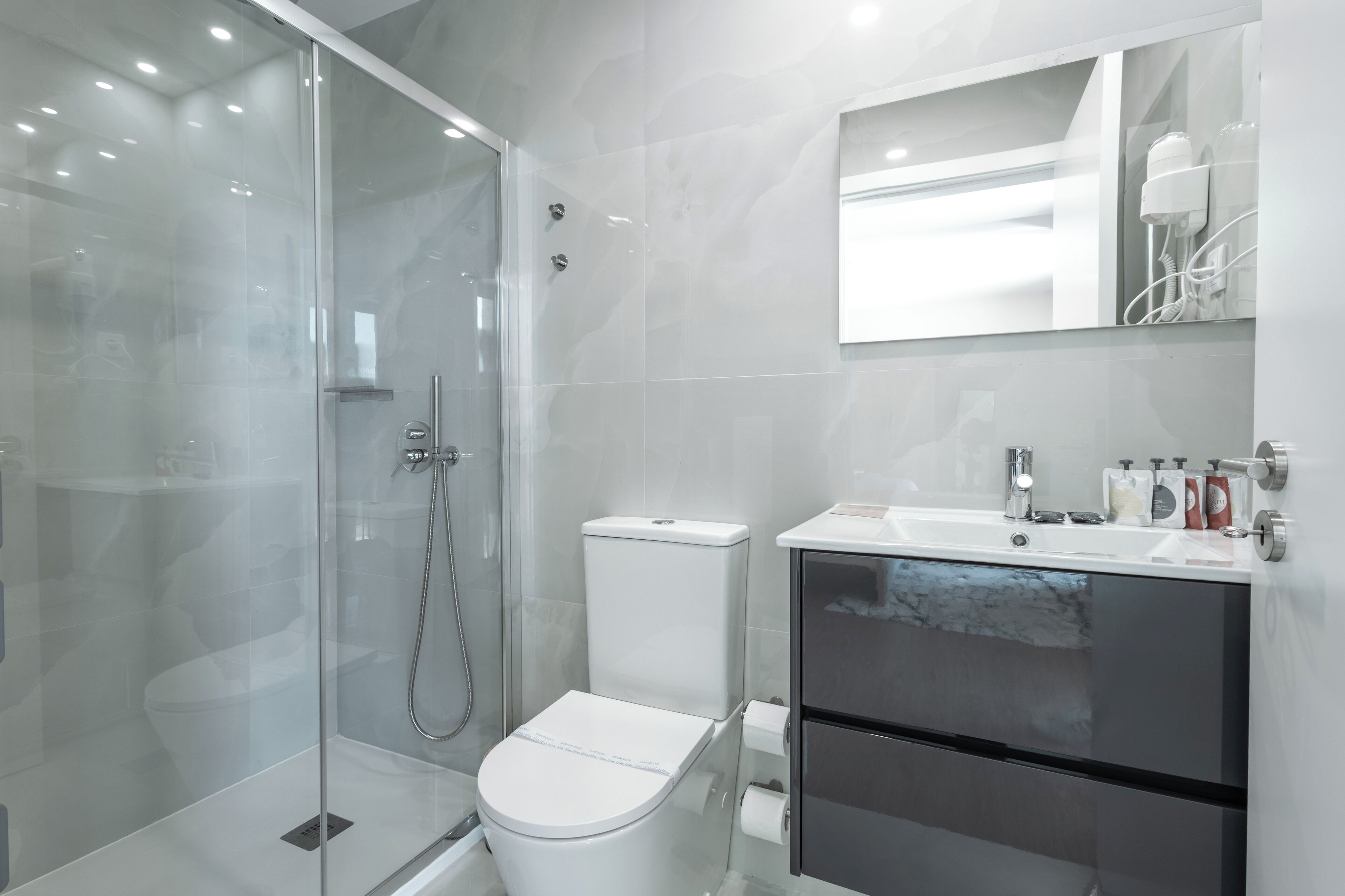 A modern bathroom with a glass-enclosed shower, a white toilet, and a vanity with a mirror.