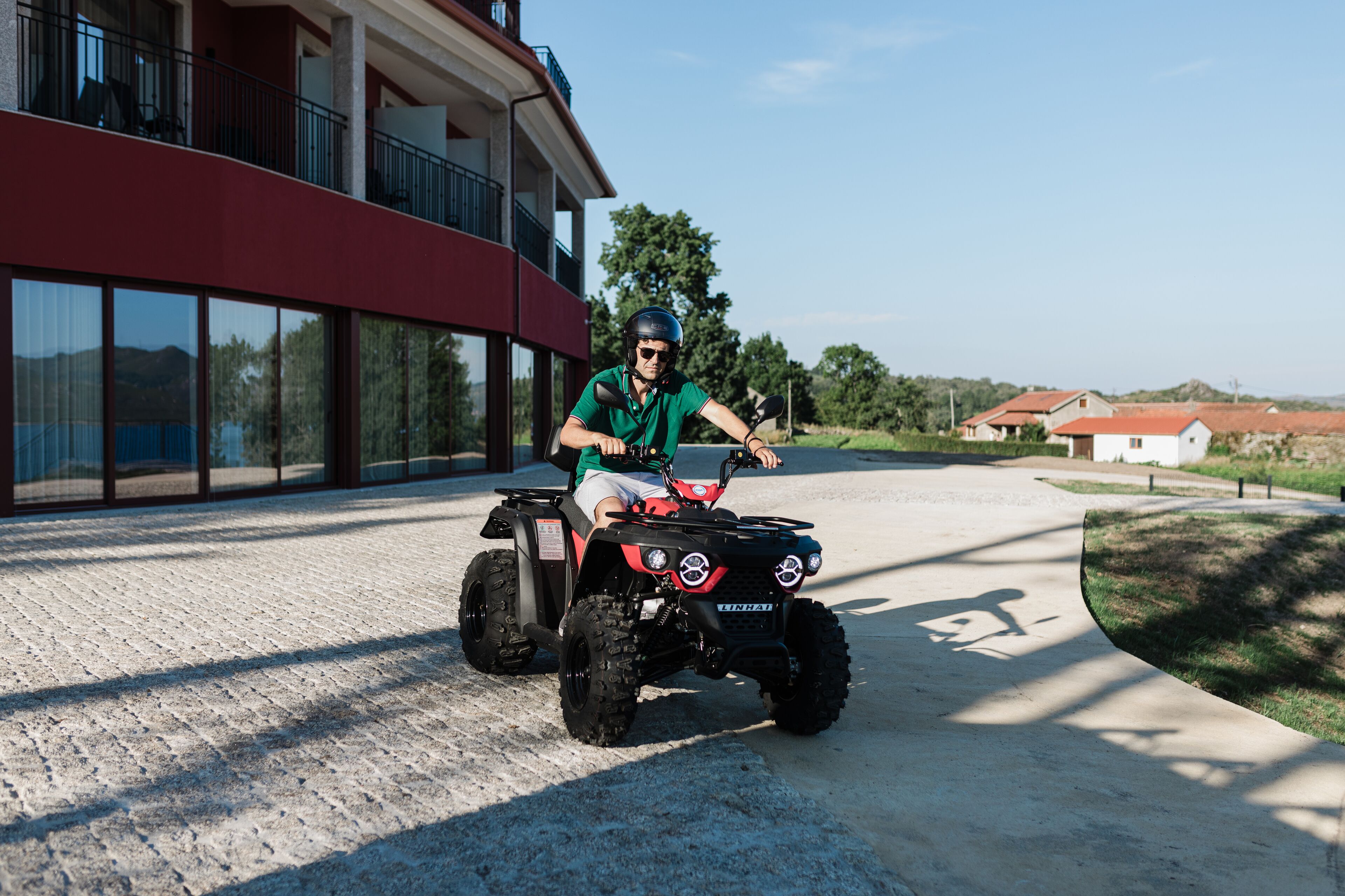 A person riding a red ATV on a concrete path.
