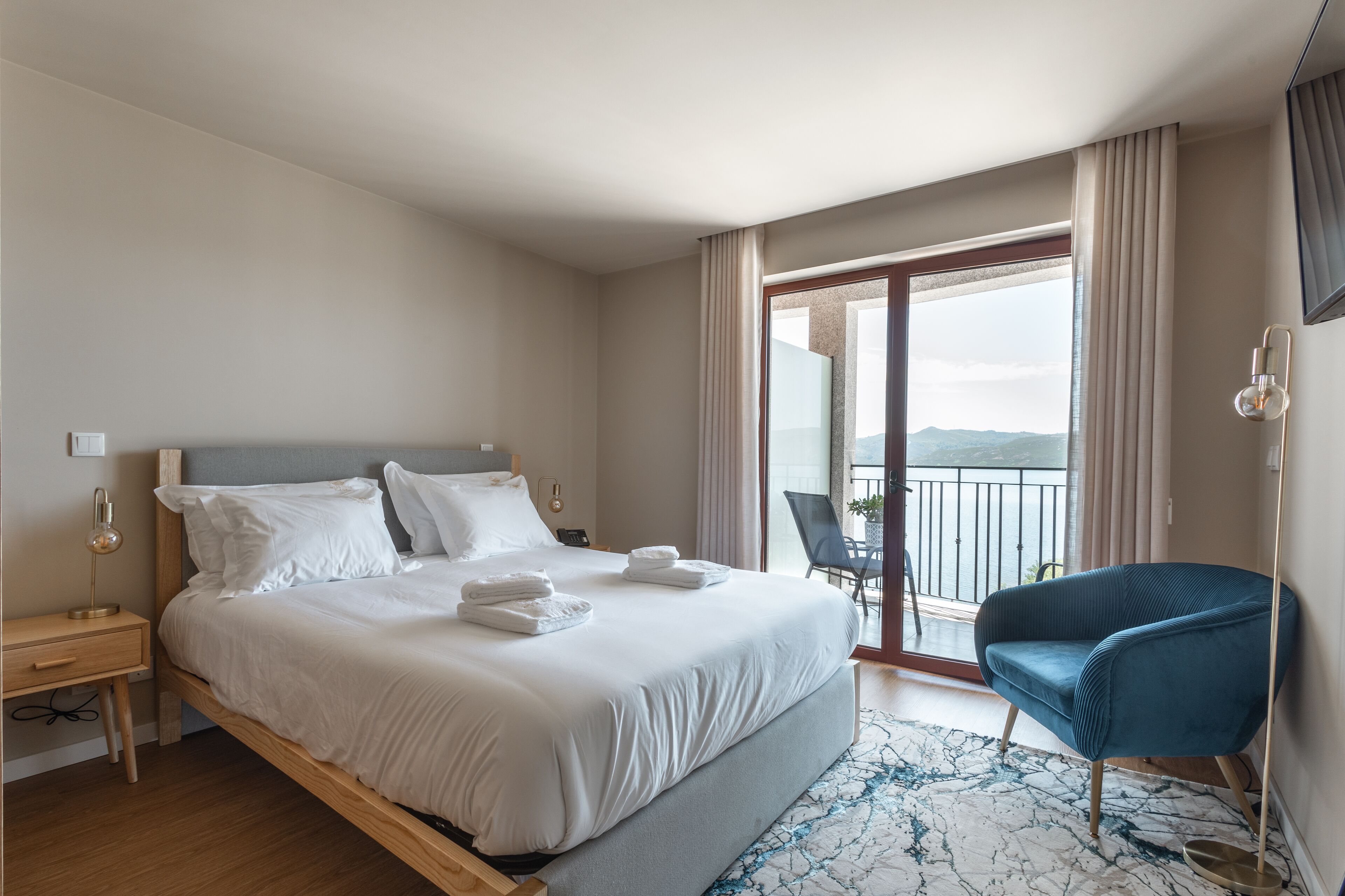 A hotel room with a bed, a chair, a desk, and a view of the outdoors.
