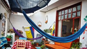 A cozy patio with a hammock, a table with a checkered tablecloth, and a bench. - Family Host (Villa de Leyva)