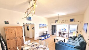 A spacious living area with a dining table set for four, a blue sofa, and a kitchen in the background. - Casa Kody - with BBQ, Fiber optic, private parking and silence.  (La Oliva)