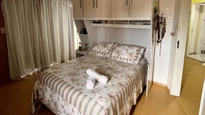 Une chambre à coucher comprenant un lit, une armoire, un miroir et une porte donnant sur une autre pièce.