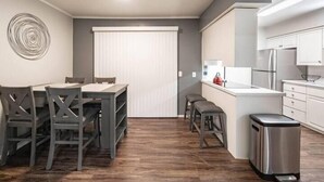 A compact kitchen with a dining area, a trash bin, and a window with blinds. - Hoff Gardens 9 - 2BR 2BA - Downtown Lubbock (Lubbock)