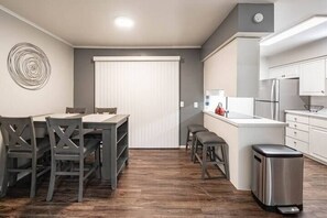 Una cocina compacta con comedor, una pequeña isla y un cubo de basura.