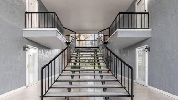 A staircase with a metal railing, leading to a second-floor landing. - Hoff Gardens 9 - 2BR 2BA - Downtown Lubbock (Lubbock)