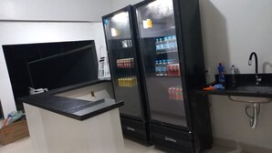 A kitchen with a black countertop, two refrigerators, a sink, and a tiled backsplash. - CRYPTOS HOTEL (Varzea Grande)