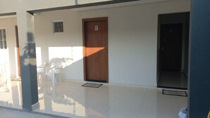 A clean, modern lobby with a wooden door marked '02', a small window, and a tiled floor. - CRYPTOS HOTEL (Varzea Grande)
