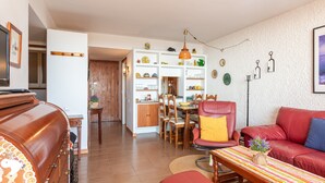 Una sala de estar con un sofá rojo, una mesa de centro de madera y un comedor con mesa y sillas de madera.