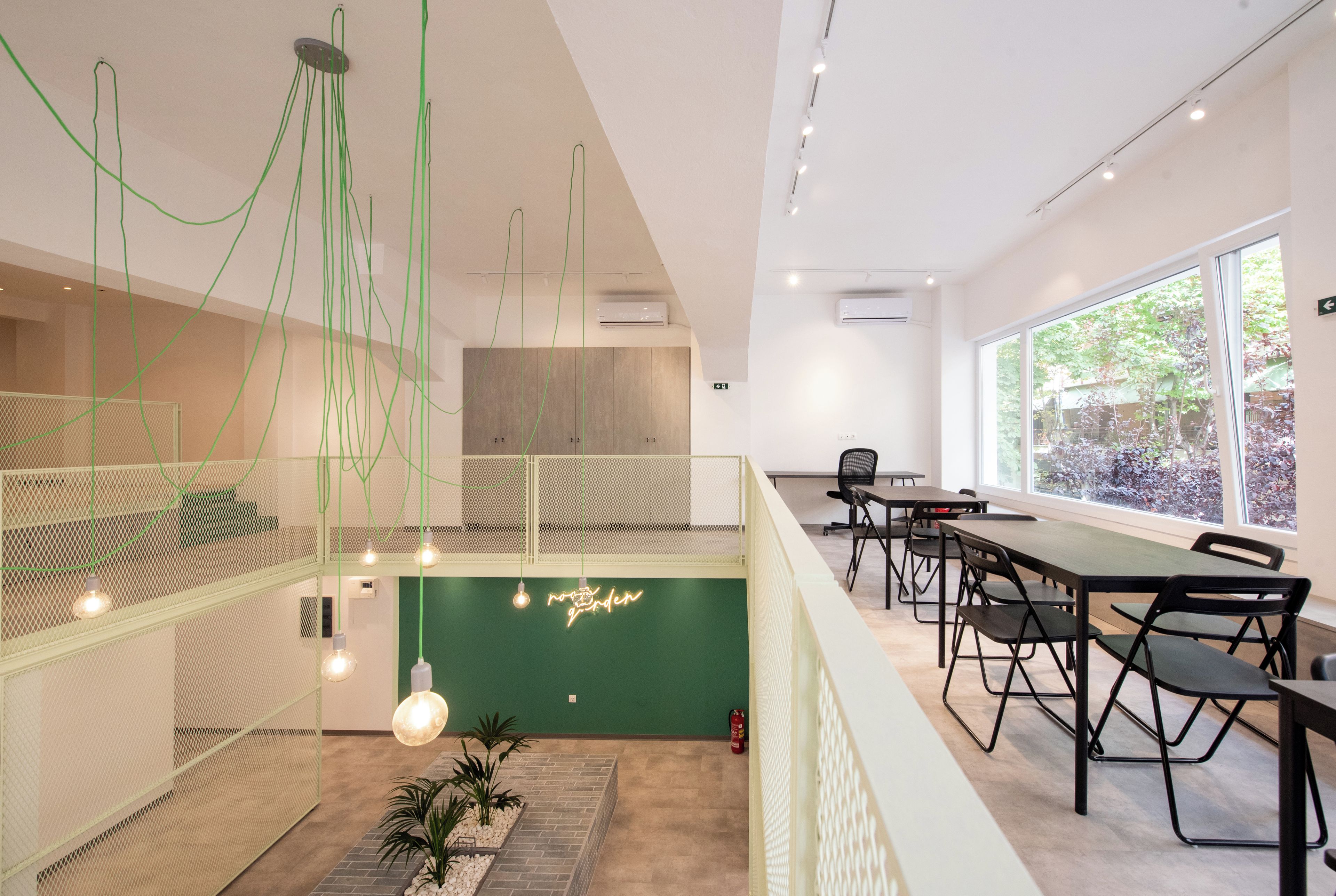 Un interior moderno con una pared verde de acento, luces colgantes y vistas al exterior.