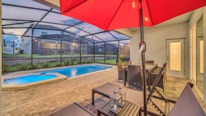 A covered outdoor area with a pool, patio furniture, and a red umbrella. - 5 En-Suites | Close to Disney! (Davenport)