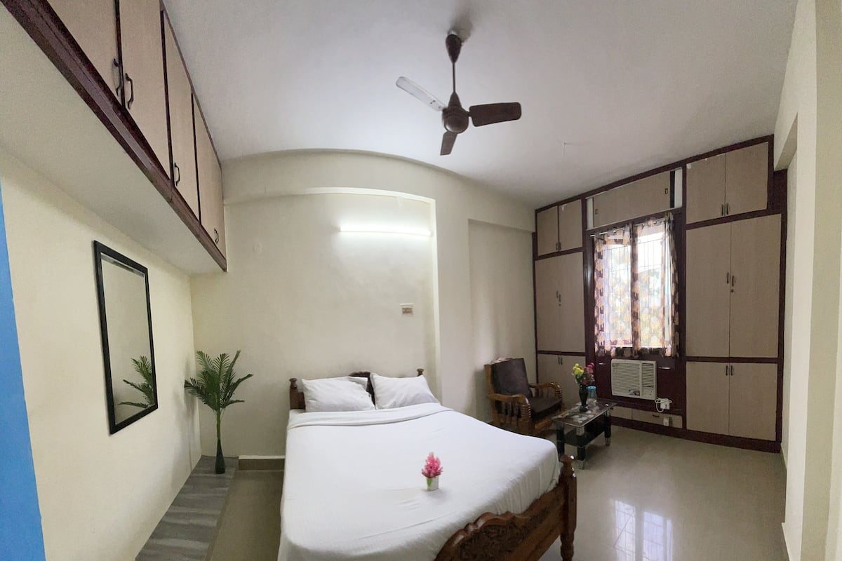 Une chambre comprenant un lit, un ventilateur de plafond, un bureau avec une chaise et des armoires.