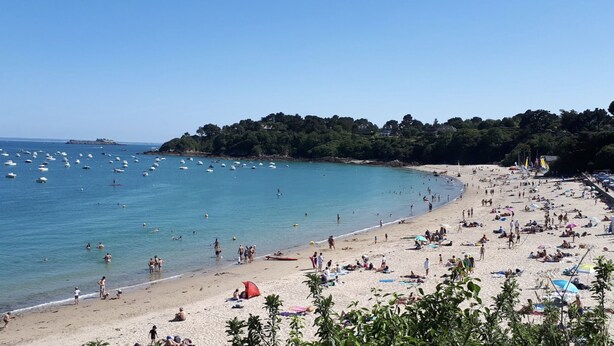 A crowded beach with people sunbathing and swimming, surrounded by a forested area and boats in the water. - Cancoon - Holiday Apartment Rental Cancale (Cancale)