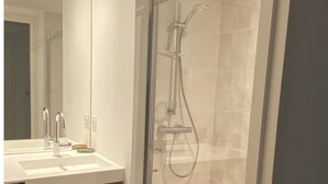 A modern bathroom with a glass-enclosed shower, a sink with a mirror, and wooden cabinetry. - Cancoon - Holiday Apartment Rental Cancale (Cancale)