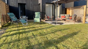 A backyard with a patio area, including a table and chairs, and a covered seating area. - Cancoon - Holiday Apartment Rental Cancale (Cancale)