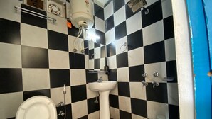 Un baño con piso a cuadros en blanco y negro, un lavamanos blanco y un inodoro.