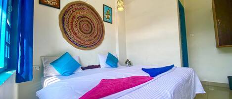 A bedroom with a bed, pillows, a wall hanging, and a motivational quote.