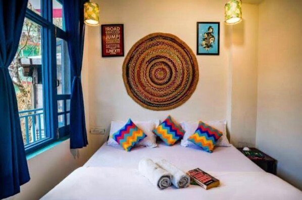 A hotel room with a bed, colorful zigzag pillows, a woven wall hanging, and a motivational poster. - Hostel Hikers World (Dharamshala)