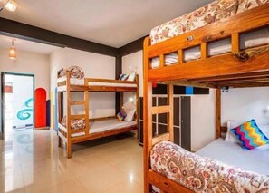 A bunk bed room with a ladder, a door, and a colorful wall decoration. - Hostel Hikers World (Dharamshala)
