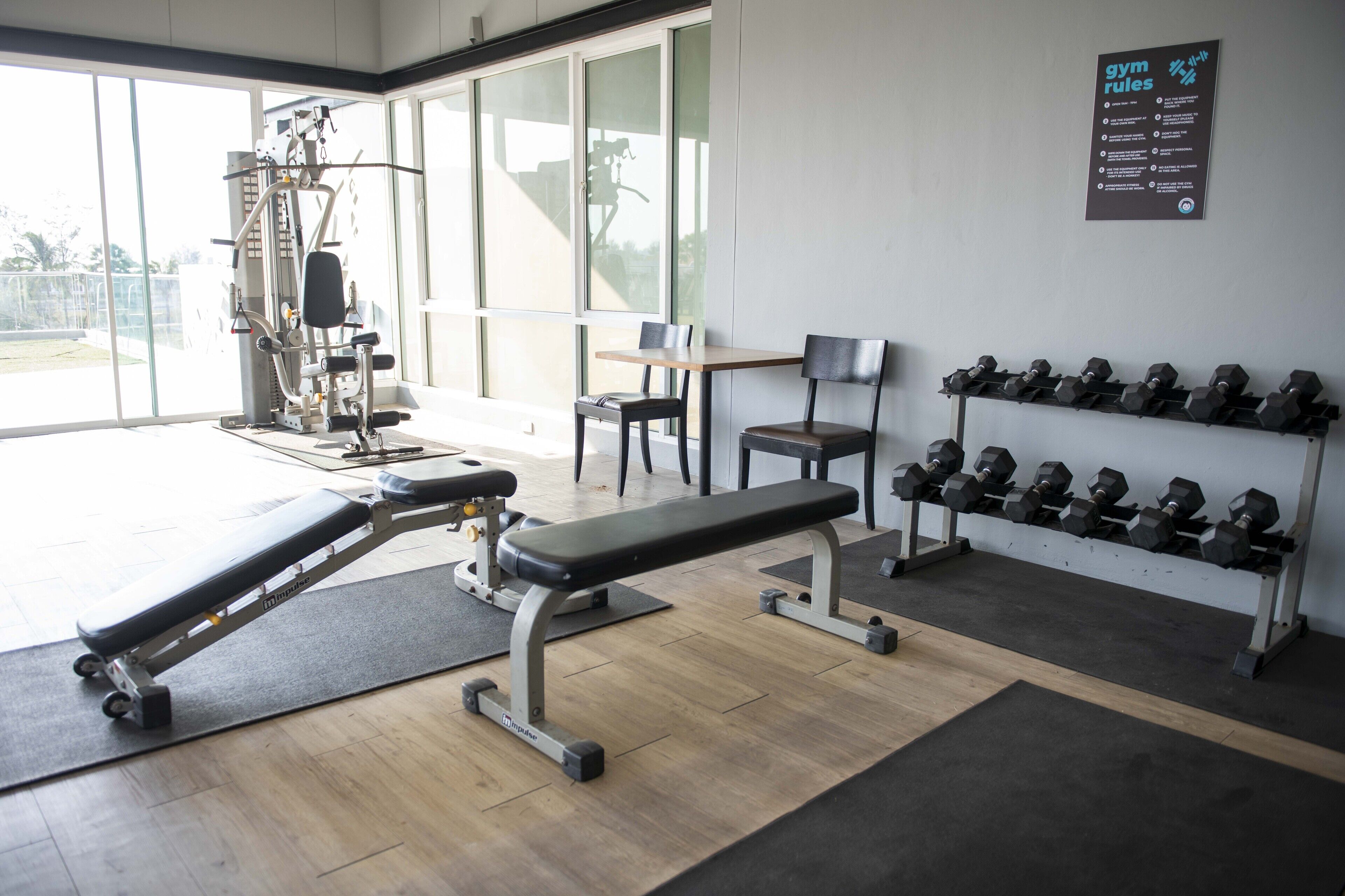 A gym with exercise equipment, a bench, and a rack of dumbbells.