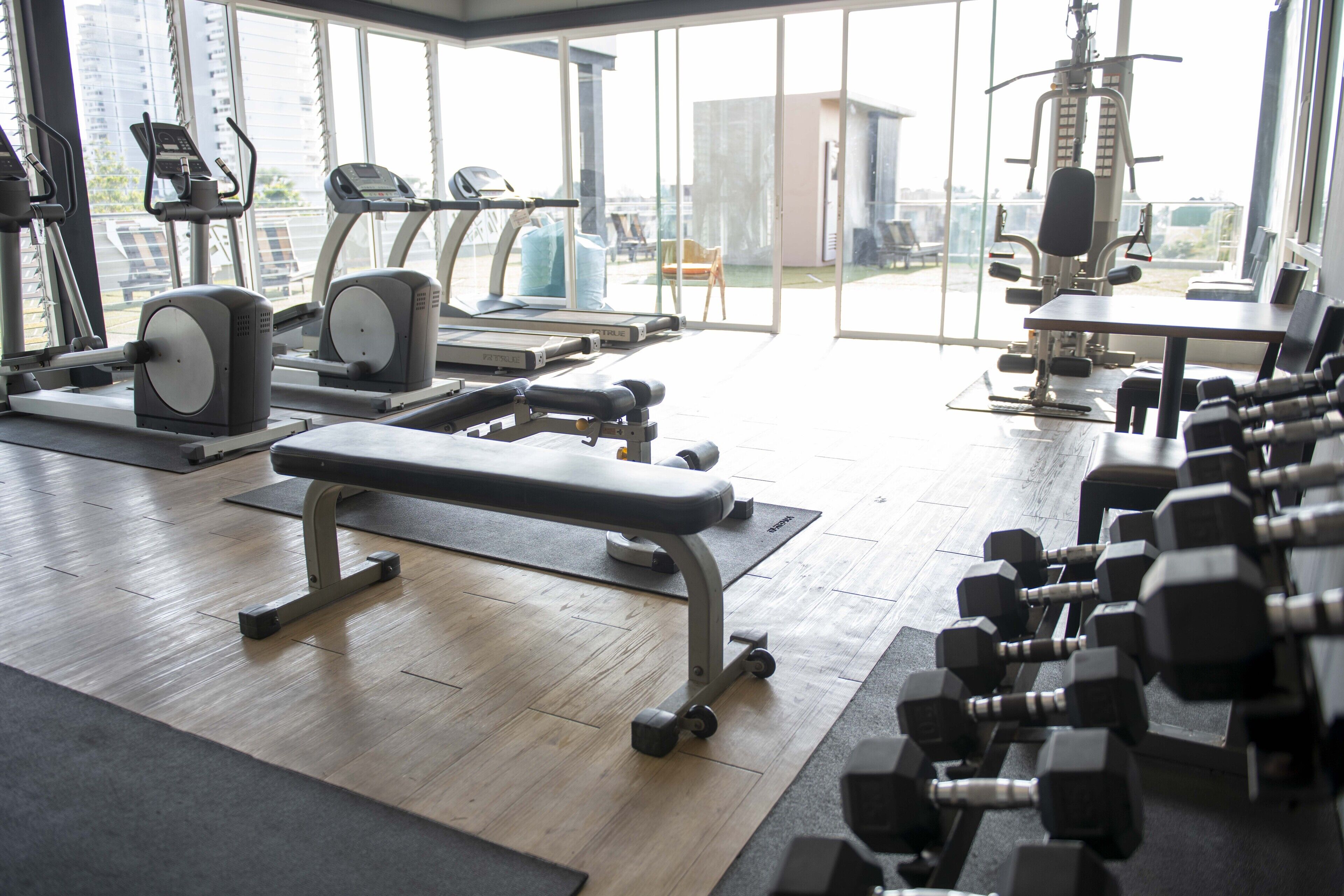 A gym with exercise equipment, a bench, and dumbbells.