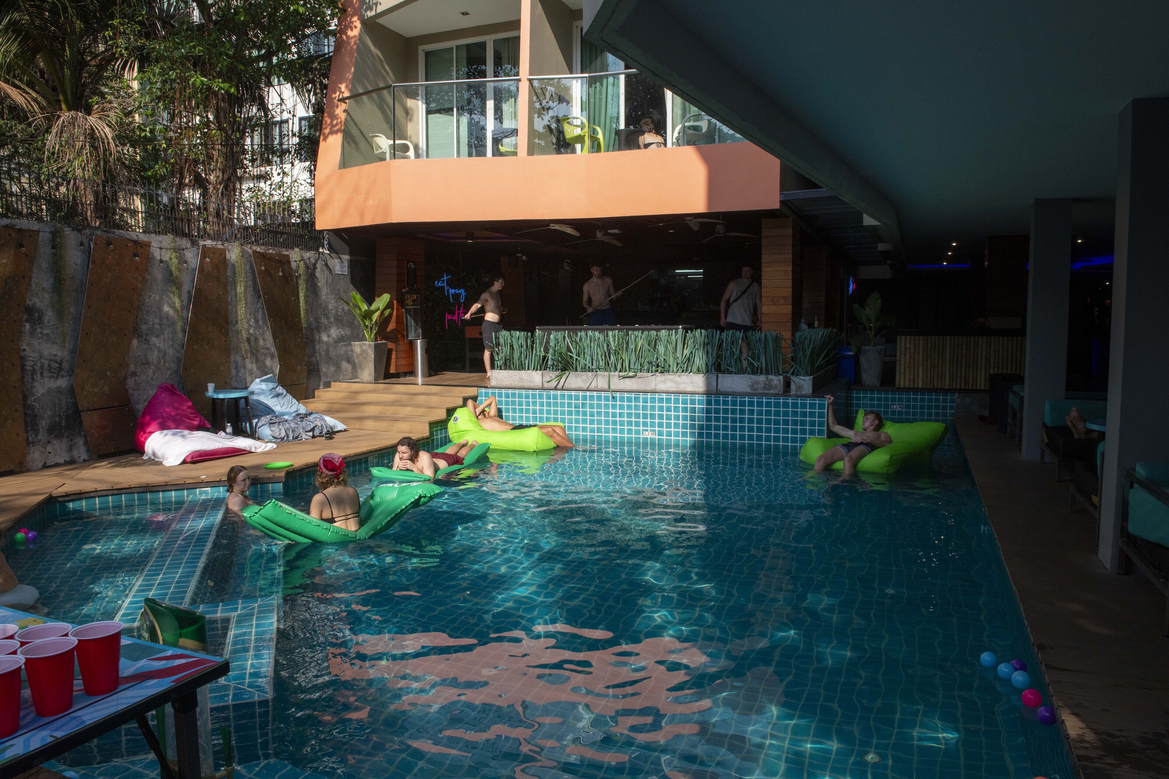 A swimming pool area with multiple people and inflatable floats.