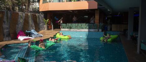 A swimming pool area with multiple people and inflatable floats.