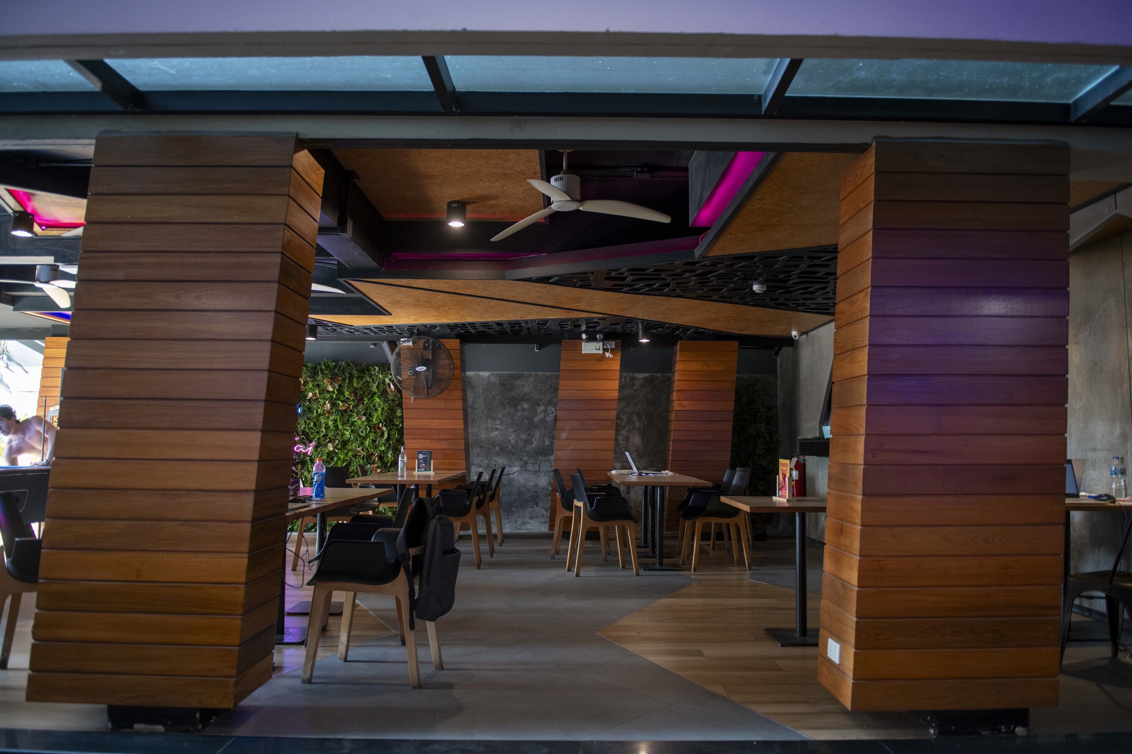 A modern interior with wooden paneling, ceiling fans, and a central seating area with tables and chairs.