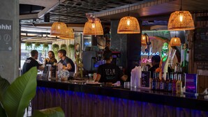 Eine Bar mit Holzwänden, hängenden Weblichtern und einer Neonreklame.