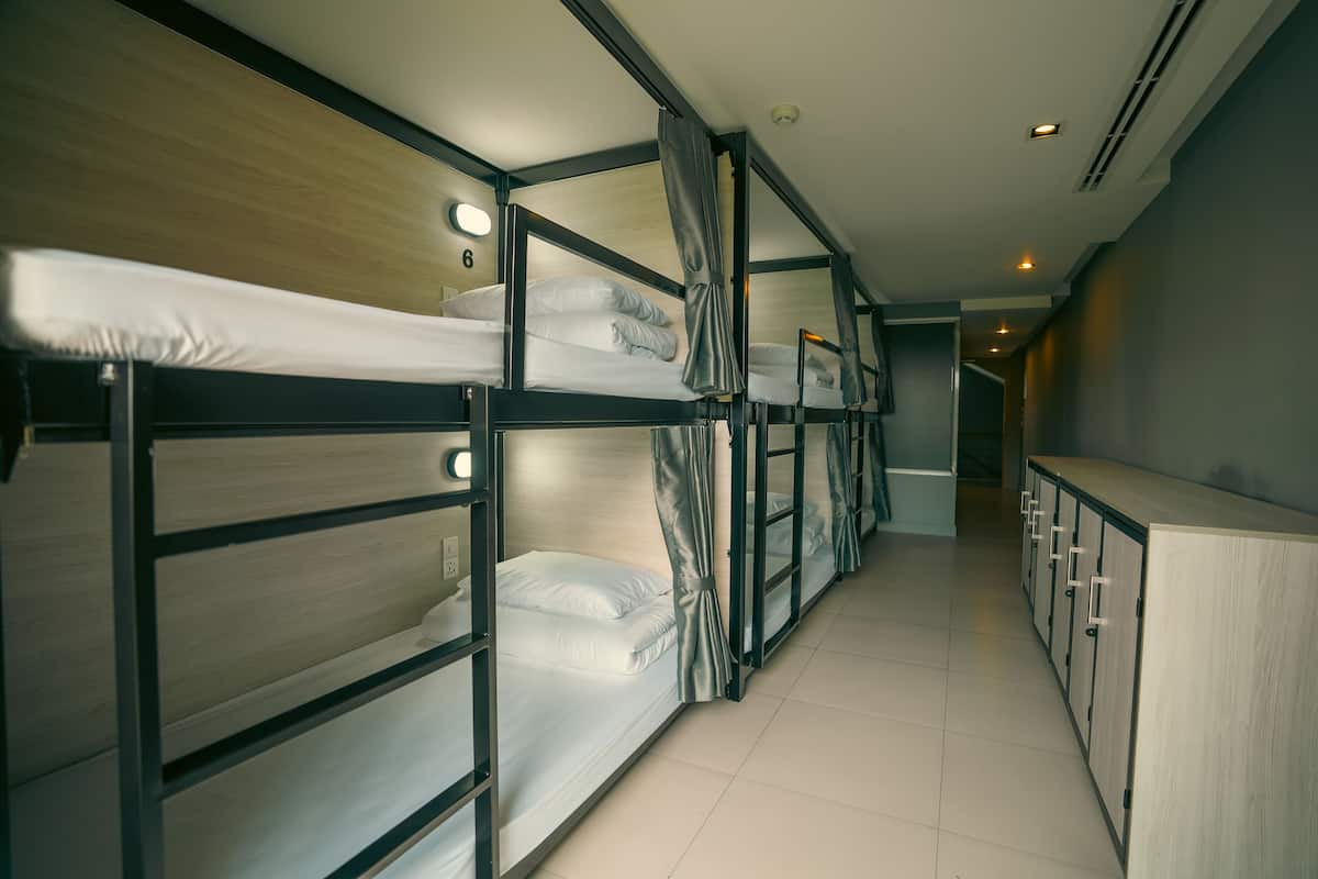 A corridor with bunk beds and a wooden cabinet.