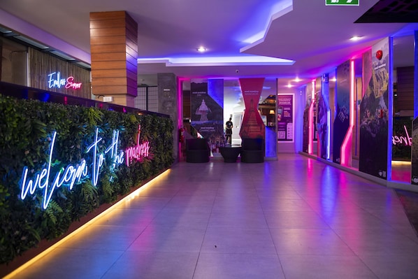 A modern hotel lobby with a neon sign reading "Welcome to the Press." - Mad Monkey Phuket (Patong)