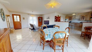 A spacious living area with a dining table, chairs, a sofa, and a television. - Le Secret des Marées (Givrand)