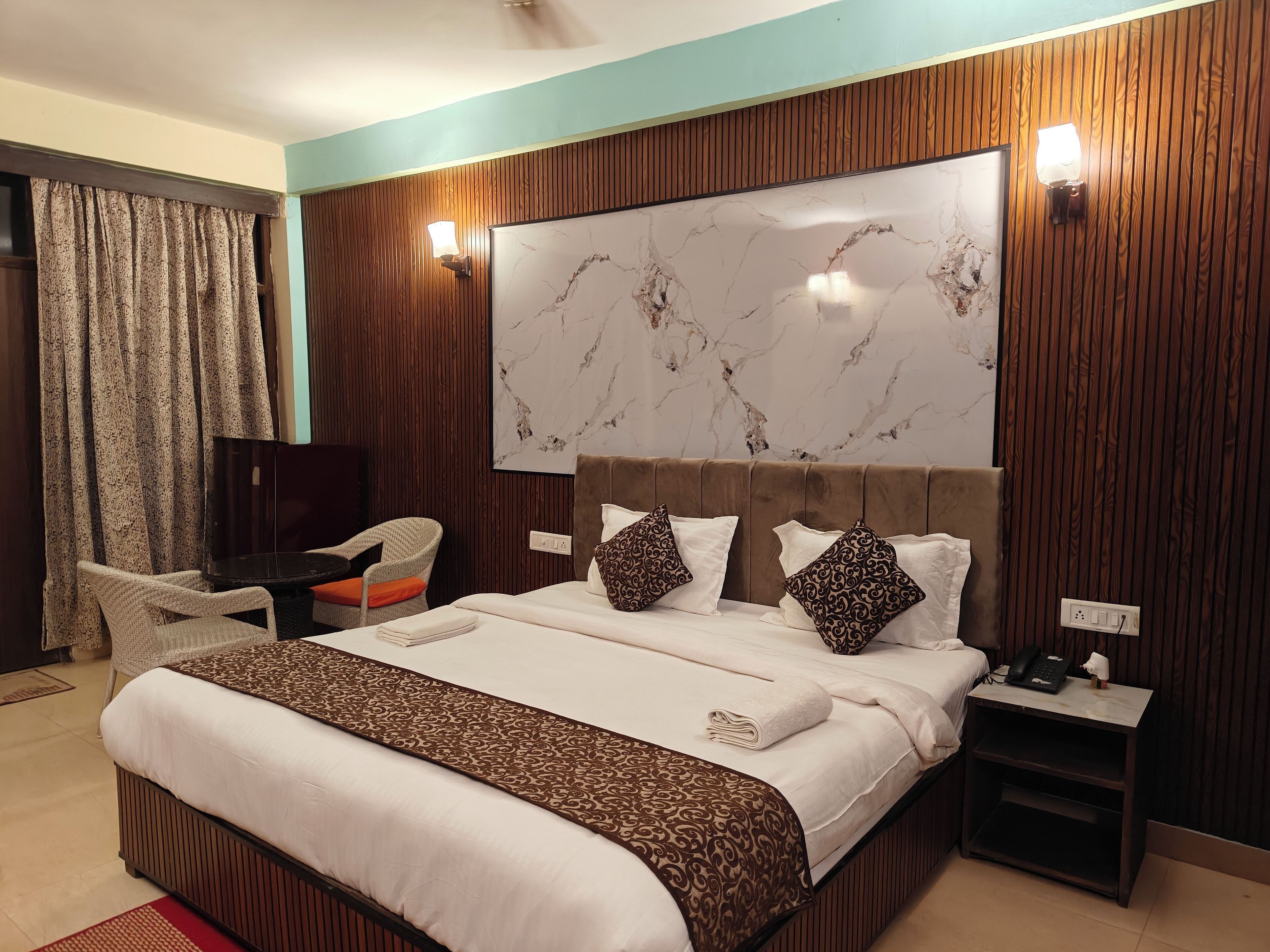 A hotel room with a large bed, a television, a desk, and a chair.