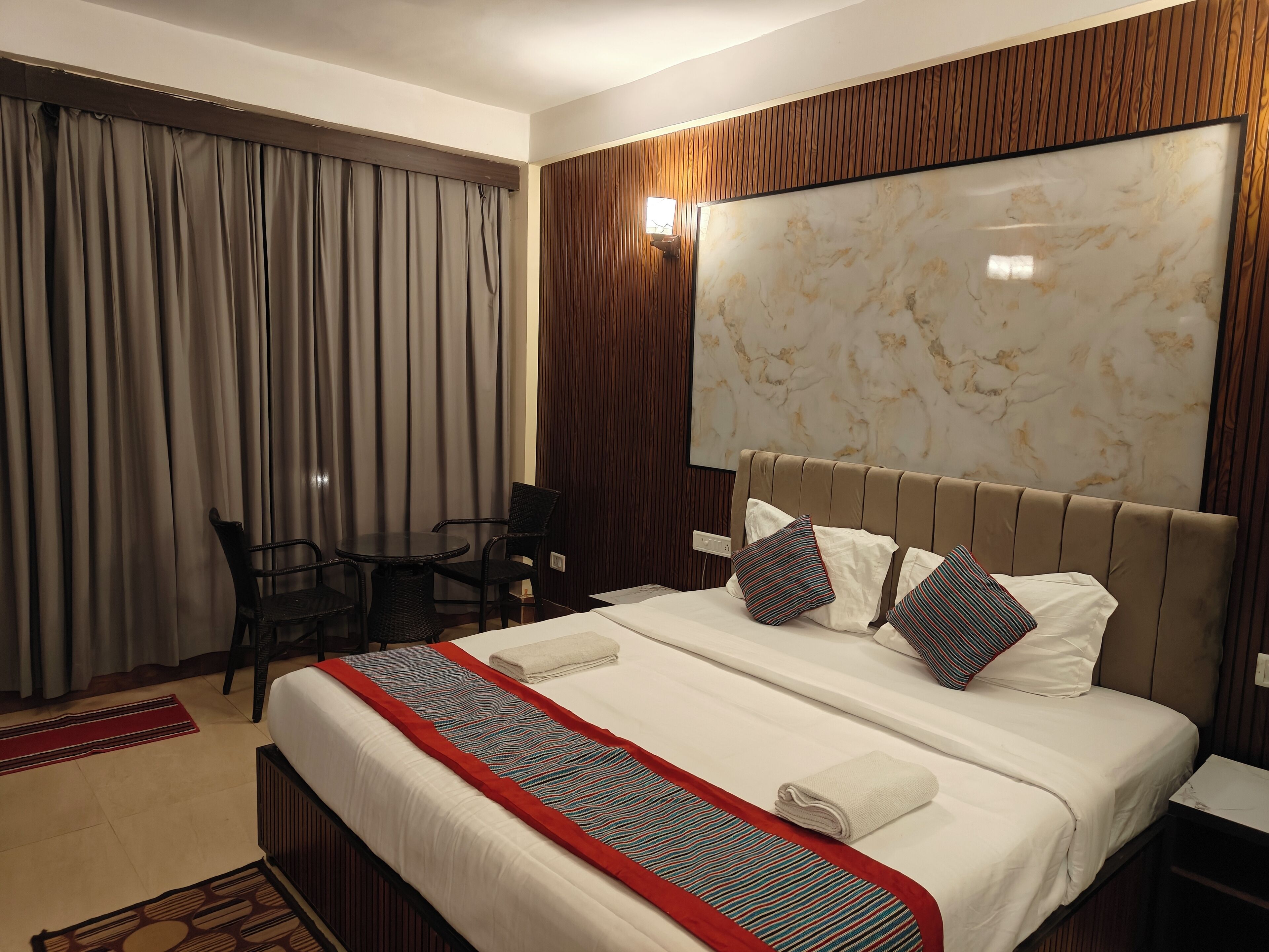 A hotel room with a bed, a desk, a chair, and a large window with curtains.