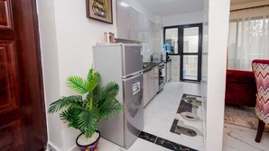 Une cuisine moderne avec des appareils en acier inoxydable, une plante en pot et une chaise rouge.