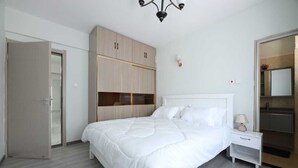 Une chambre à coucher avec un grand lit, une armoire, une table de chevet et un miroir.