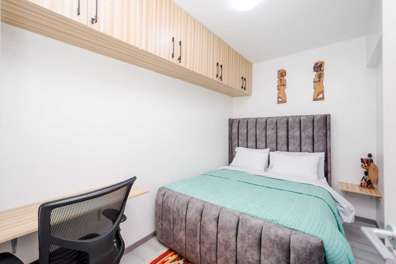 A bedroom with a bed, a desk, and a chair.