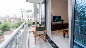 Un balcon avec une table et des chaises pour prendre les repas, un téléviseur et une vue sur le paysage urbain.