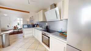 Une cuisine moderne avec des meubles blancs, un plan de travail noir et des appareils en acier inoxydable.