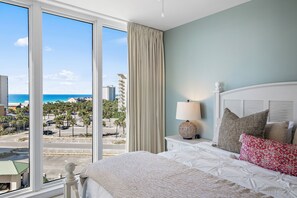 Ein Hotelzimmer mit großem Fenster und Blick auf Strand und Palmen.