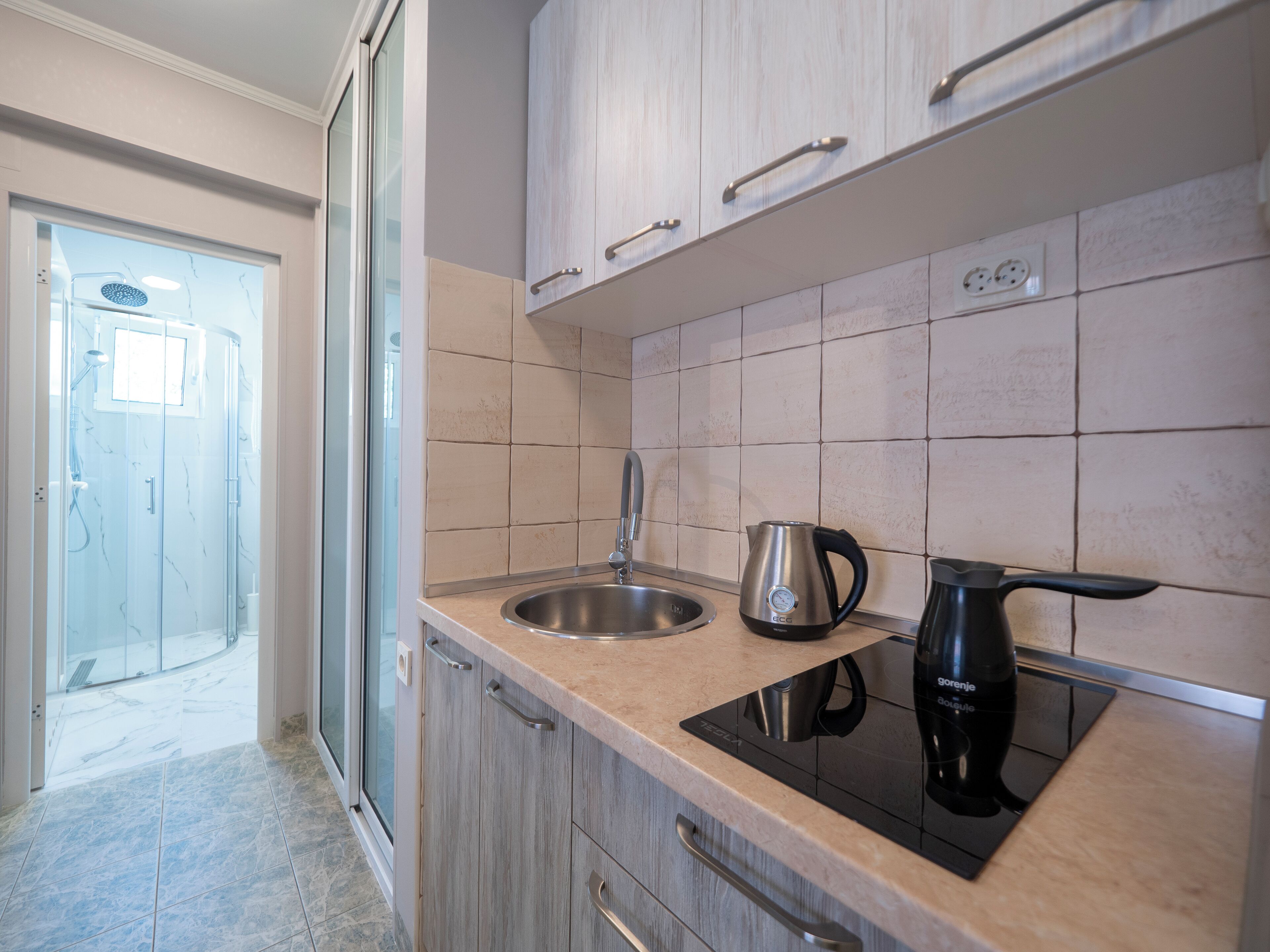 A modern kitchen with a sink, kettle, and induction cooktop.