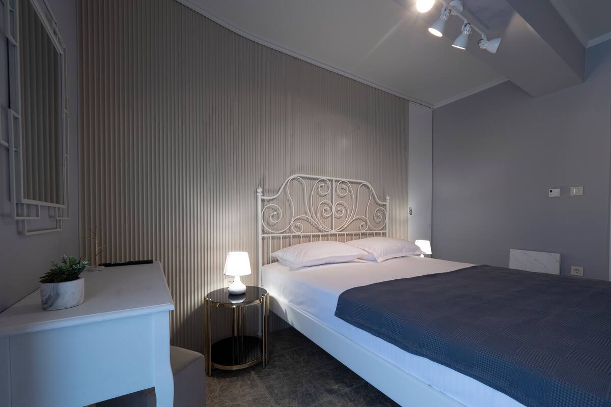 Quarto moderno com cama, mesa de cabeceira, abajur e planta em vaso.