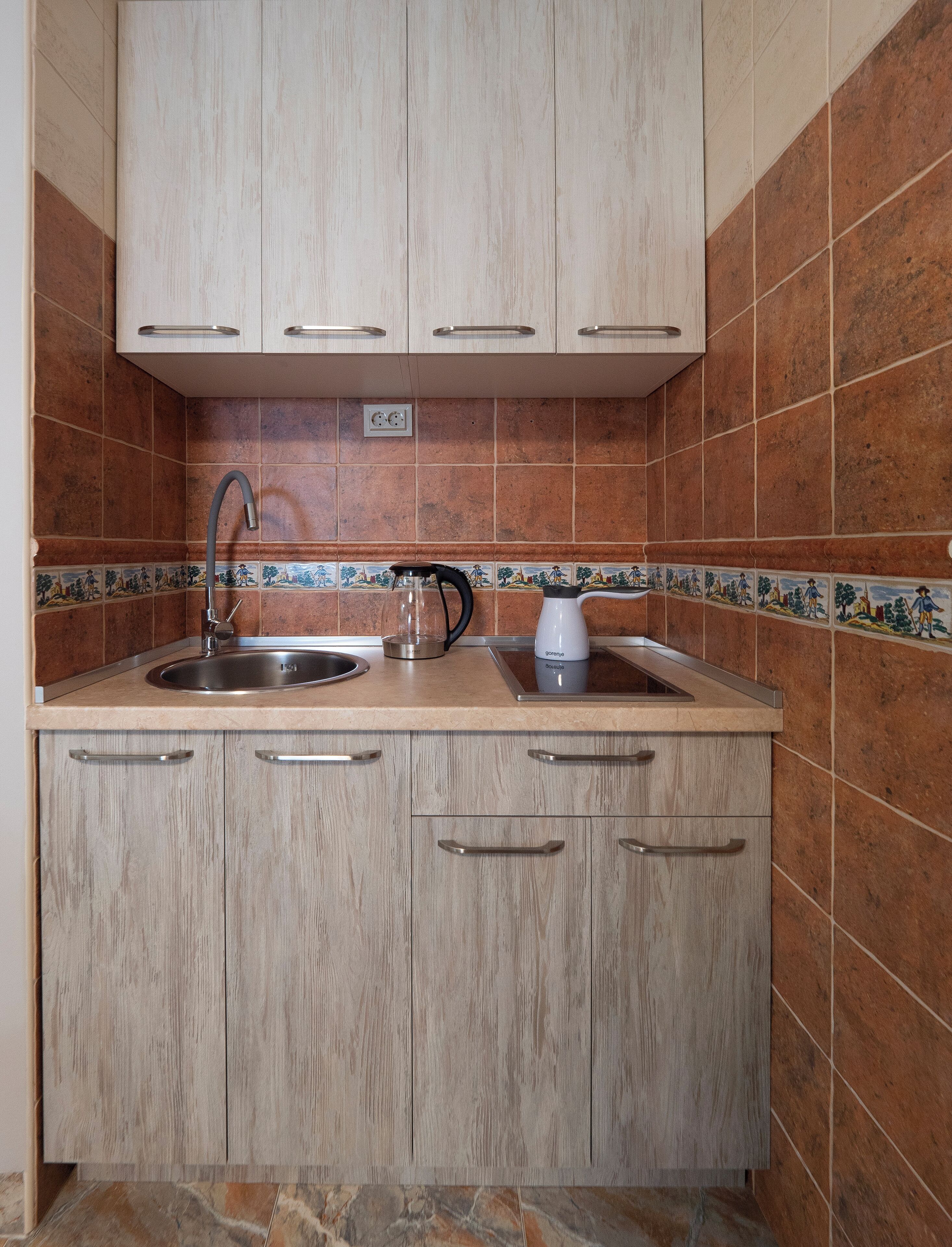 A kitchen with two sinks, a coffee maker, and a tiled backsplash.
