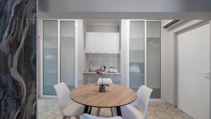 Een moderne keuken met witte kastjes, een ronde houten tafel en witte stoelen.