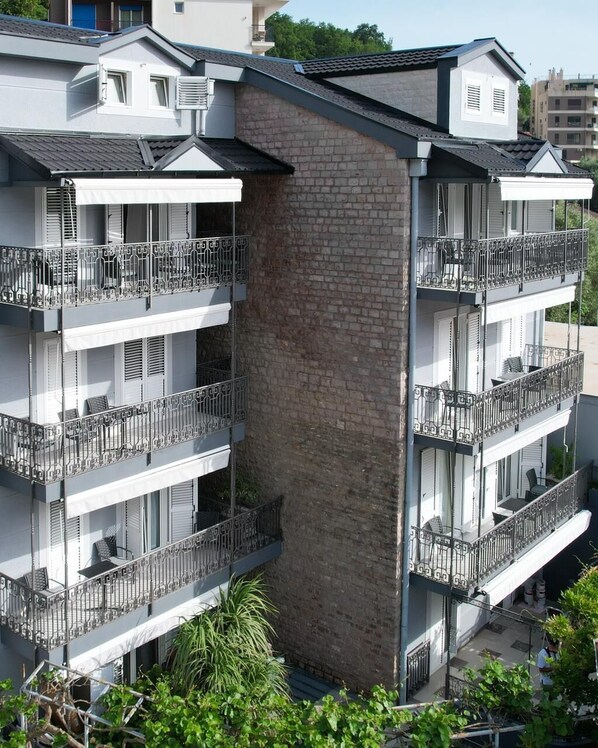 A multi-story residential building with balconies, brick facade, and a flat roof. - Apartments Cataleya Przno (Pržno)