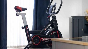 Uma bicicleta ergométrica em um quarto com uma escrivaninha e um armário.