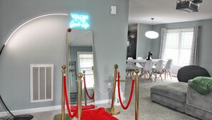 A room with a red carpet leading to a mirror, a grey sofa, and a dining area with white chairs. - 5 Bedroom Home, 13 mins away from Skyline Drive (Waynesboro)