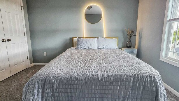 A bedroom with a bed, a bedside table with a vase, a mirror, and a window. - 5 Bedroom Home, 13 mins away from Skyline Drive (Waynesboro)