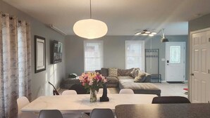 A dining area with a table and chairs, a sofa, and a vase of flowers. - 5 Bedroom Home, 13 mins away from Skyline Drive (Waynesboro)