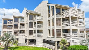 Un edificio residencial de varios pisos con balcones, una zona de estacionamiento techada y un letrero que dice 'The Village'.