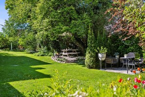 Un jardín con una mesa de picnic, sillas y una parrilla.